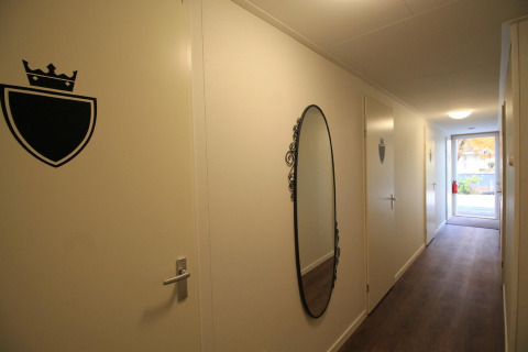 En gang i Residence De Eese 22 i Holland, med spejl, døre og skiltet skjold med krone.