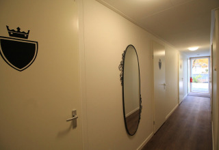 En gang i Residence De Eese 22 i Holland, med spejl, døre og skiltet skjold med krone.