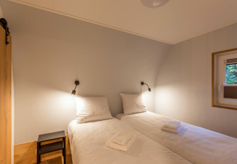 Zwei Einzelbetten mit weißer Bettwäsche und Leselampen in einem Zimmer der Residence De Eese 22, Niederlande.