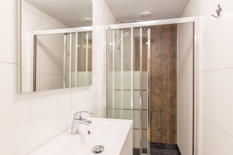 Moderne badeværelse på Residence De Eese 22 i Holland med brusekabine, spejl og hvid vask.