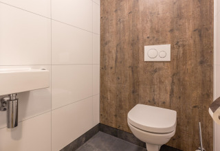 Moderne toilet og håndvask med træmønster væg på badeværelse hos Residence De Eese 22 i Holland.