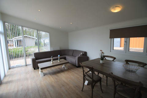 Woonkamer in chalet Residence de Eese 20 in Nederland met hoekbank, eettafel en grote ramen.