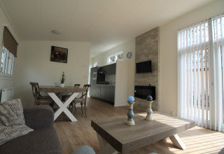 Modern chaletinterieur met eettafel, bank, groot raam en houten vloer bij Residence de Eese 20, Nederland.