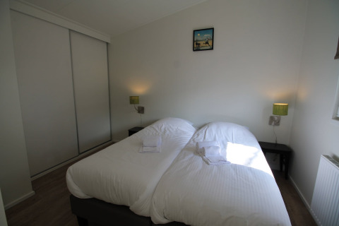Slaapkamer met twee eenpersoonsbedden, wit beddengoed, nachtkastjes en groene lampen in Residence de Eese 20, Nederland.