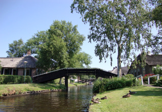 Prachtig uitzicht op het kanaal bij Residence De Eese 22 lodge in Nederland met brug en eenden op het gras.