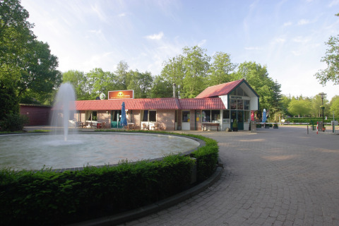 Buitenaanzicht van Residence de Eese 20 in Nederland, met fontein en receptiegebouw op de voorgrond.