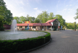 Buitenaanzicht van Residence de Eese 20 in Nederland, met fontein en receptiegebouw op de voorgrond.