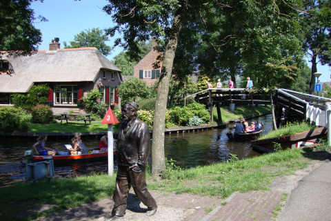 Chalet Residence de Eese 20 in Nederland met kanaal, boten, brug, standbeeld en groene omgeving.