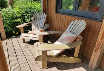 Twee houten stoelen op een zonnige veranda van een tiny house voor twee personen in Nederland.