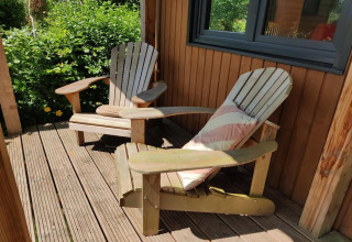 Dos sillas de madera en la terraza soleada de una tiny house para dos personas en los Países Bajos.