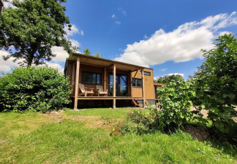 Tiny house voor 2 personen in Nederland, omgeven door groen en natuur met een overdekt terras.