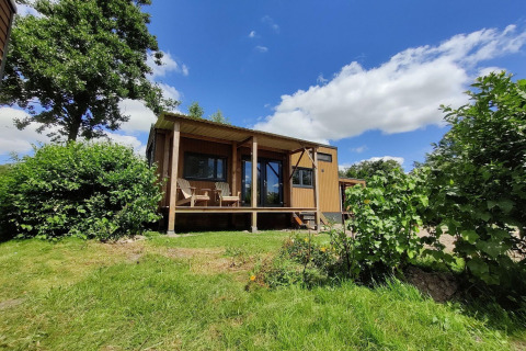 Casa pequeña para 2 personas en Países Bajos, rodeada de naturaleza y cielo azul con algunas nubes.