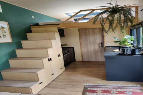 Interior de una tiny house moderna en los Países Bajos con escalera, cocina y plantas colgantes.