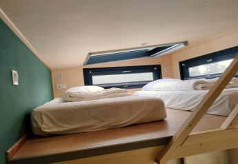 Slaaploft met twee bedden en dakraam in een Tiny House voor 2 personen in Nederland gefotografeerd.