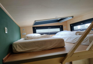 Dormitorio tipo loft con dos camas y claraboya en Tiny House para 2 personas en los Países Bajos.