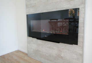 Moderne elektrische haard aan een lichte wand, weerspiegelt eetkamer in Residence de Eese 20, Nederland.