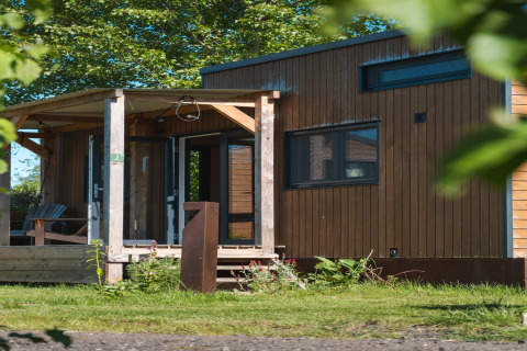 Acogedora tiny house para 2 personas en Países Bajos, rodeada de vegetación y luz natural.