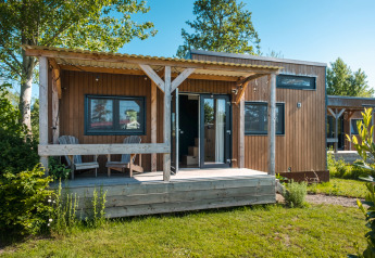 Klein houten tiny house met veranda en twee stoelen, Tiny House voor 2 personen in Nederland.