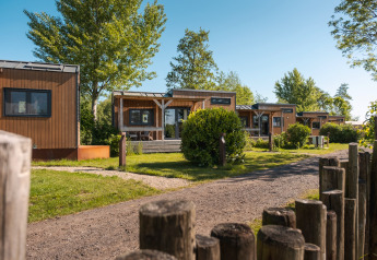 Moderne tiny houses voor 2 personen omringd door groen en bomen op een vakantiepark in Nederland.