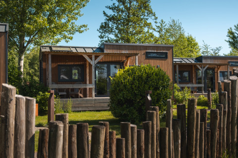 Acogedora tiny house de madera para 2 personas en Países Bajos, rodeada de áreas verdes y valla rústica.