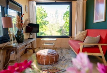 Woonkamer van een tiny house voor 2 personen in Nederland met rood bankje en groot raam met uitzicht.