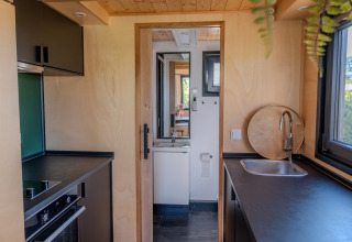 Compact kitchen and bathroom area in a tiny house for two people in the Netherlands, modern decor.