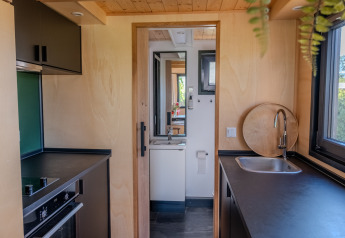 Compact kitchen and bathroom area in a tiny house for two people in the Netherlands, modern decor.