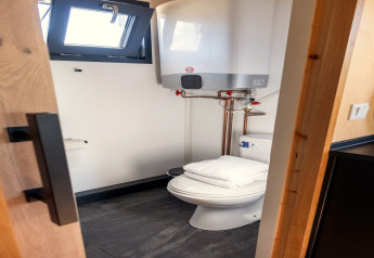 Kleine badkamer met toilet, handdoek en boiler in een tiny house voor 2 personen in Nederland.