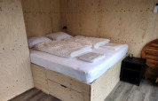 Schlafbereich in der Wetland Cabin für 2 Personen mit Bett und heller Holzverkleidung in Friesland, Niederlande.