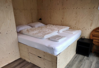 Schlafbereich in der Wetland Cabin für 2 Personen mit Bett und heller Holzverkleidung in Friesland, Niederlande.