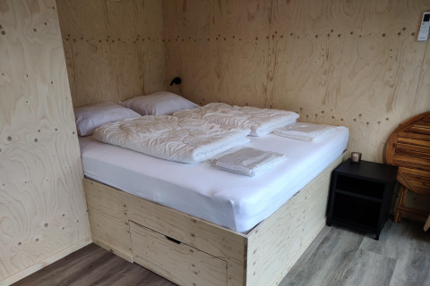 Soveområde i Wetland Cabin for 2 personer med dobbeltseng, sengetøj og træpaneler, Friesland, Holland.