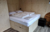 Dormitorio en la Wetland Cabin para 2 personas con cama y paredes de madera clara en Friesland, Países Bajos.