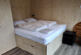 Soveområde i Wetland Cabin for 2 personer med dobbeltseng, sengetøj og træpaneler, Friesland, Holland.