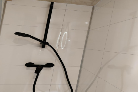 Moderne zwarte douche op witte tegels in de Wetland Cabin voor 2 personen bij Boetiekpark de Kas, Nederland.