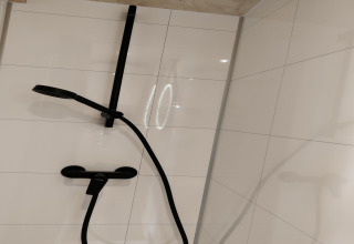 Douche noire moderne sur des carreaux blancs, dans la Wetland Cabin 2 personnes à Boetiekpark de Kas, Pays-Bas.