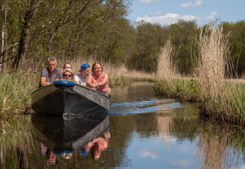 Een gezelschap vaart met een bootje door een kanaal naast de Large Green House lodge in Nederland.