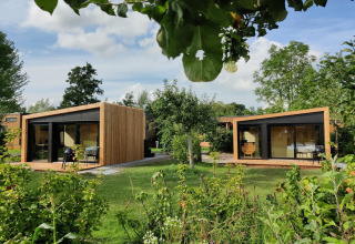 Dos cabañas modernas de madera con grandes ventanales en un jardín verde en Boetiekpark de Kas, Scherpenzeel, Friesland.