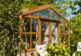 Glazen lodge met gouden frames omringd door groen bij Large Green House 4 persons, Nederland.