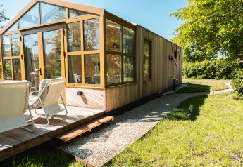 Buitenzicht op Large Green House lodge voor 4 personen met zonnig terras en tuinstoelen buiten.