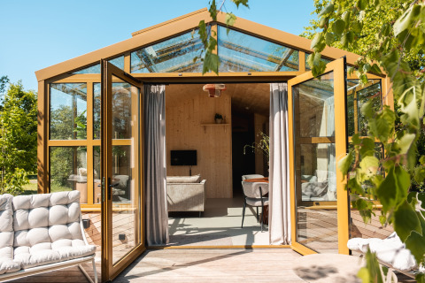 Grande lodge in serra con porte aperte, interni moderni e vista verde nei Paesi Bassi.