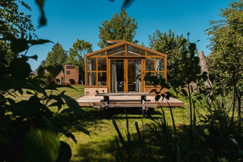Moderno lodge 'Large Green House' per 4 persone nei Paesi Bassi, circondato da alberi e prato verde.