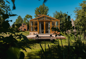 Moderne lodge ‘Large Green House’ voor 4 personen in Nederland, omgeven door groene bomen en gras.