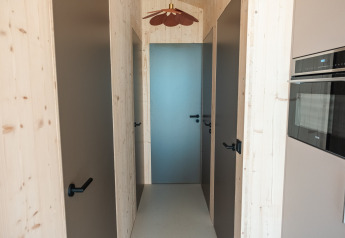 Gang met lichte houten muren, vier deuren en moderne inrichting in de lodge Large Green House 4 personen in Nederland.