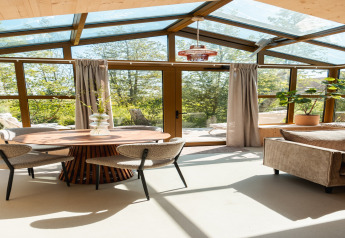 Lichte leefruimte in Large Green House 4 persons lodge, glazen dak, ronde tafel, stoelen, Nederland.