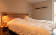 Knusse lodge slaapkamer met tweepersoonsbed, houten accenten en warme verlichting naast het raam.