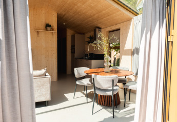 Interieur van een moderne houten lodge met ronde tafel, vier stoelen en keuken in Large Green House, Nederland.