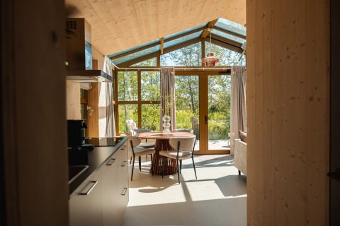 Interno della lodge Large Green House per quattro persone nei Paesi Bassi con ampie finestre e vista natura.