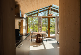 Interno della lodge Large Green House per quattro persone nei Paesi Bassi con ampie finestre e vista natura.
