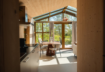 Interieur van de Large Green House lodge voor vier personen in Nederland met grote ramen en natuurzicht.