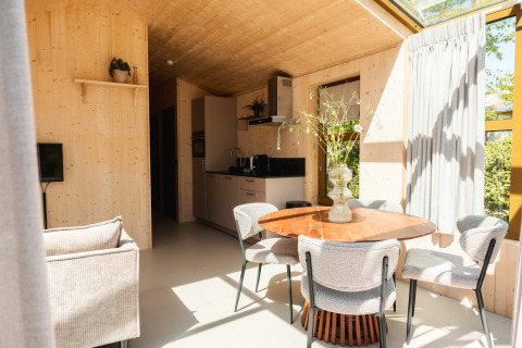 Interno luminoso e moderno di una lodge con tavolo in legno e grandi finestre nei Paesi Bassi.